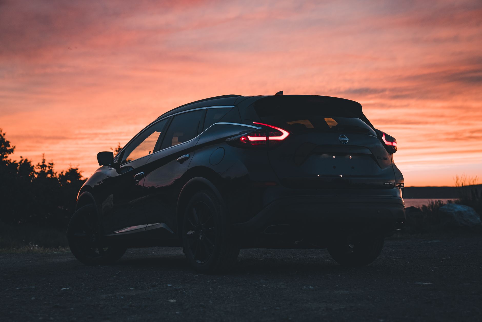 Ilustrasi: Silhouette of a Nissan Murano SUV captured at sunset, showcasing a vibrant orange sky.