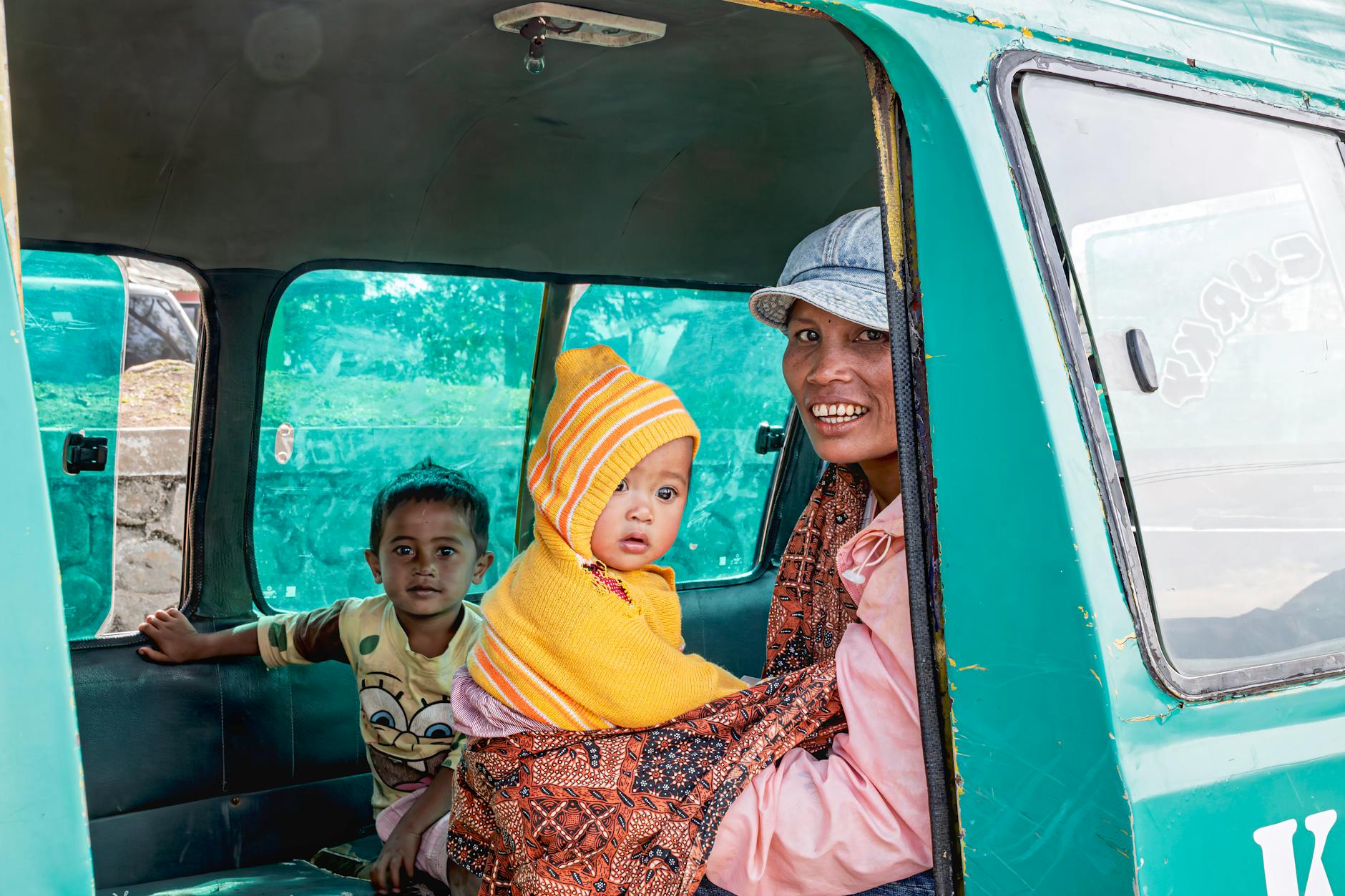 Ilustrasi: A family with children inside a green minivan in Indonesia. Smiling faces and vibrant colors.
