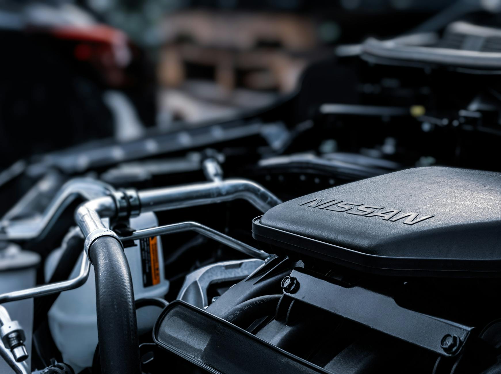 Ilustrasi: Detailed view of a car engine compartment with visible Nissan branding.
