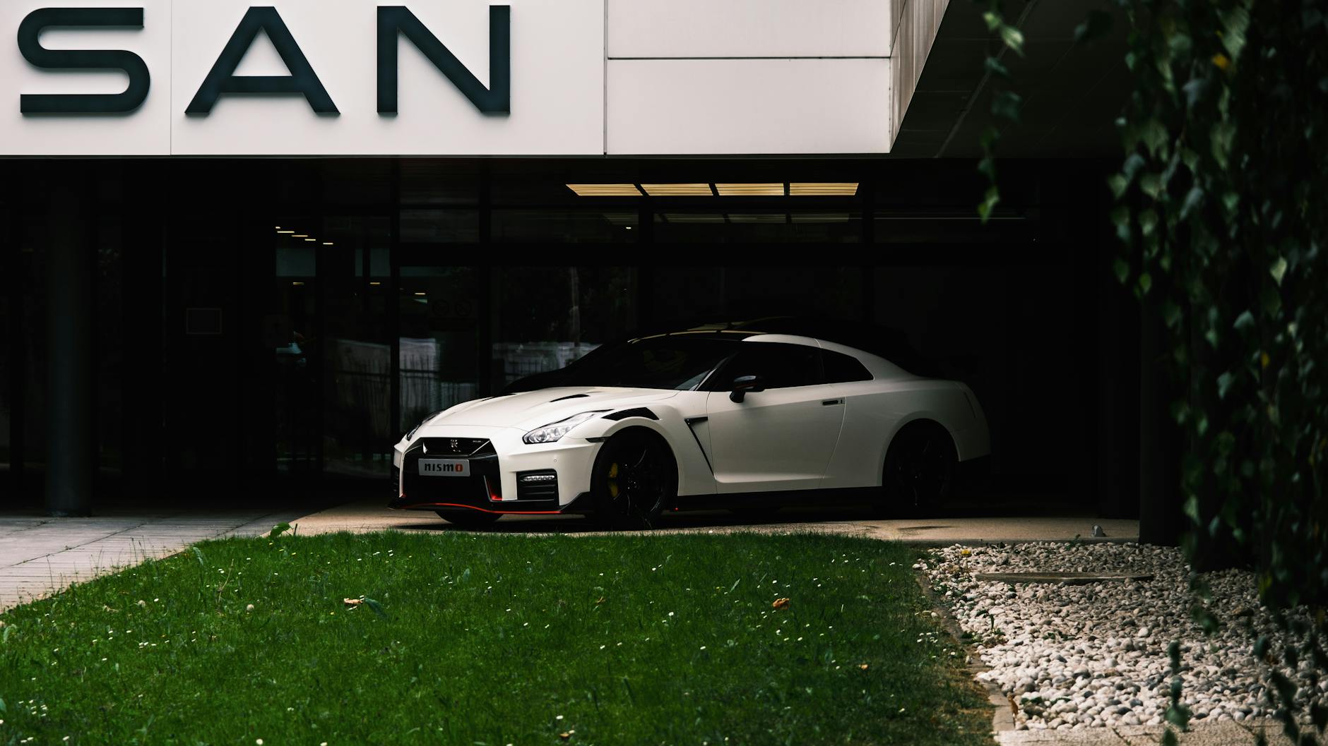 Ilustrasi: Capture of a white Nissan GT-R NISMO parked at a dealership entrance, showcasing its modern design.