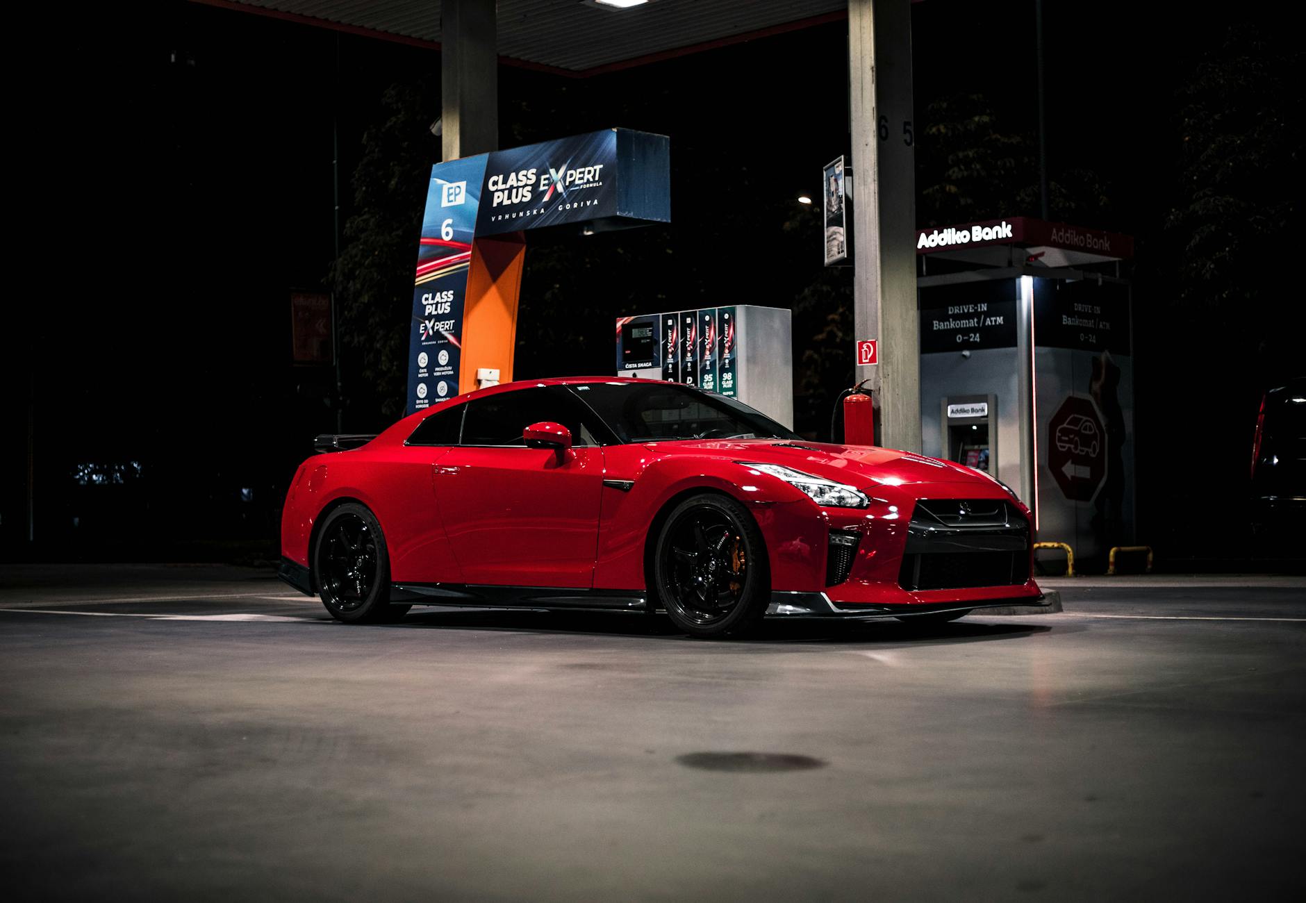 Ilustrasi: Red Nissan GTR parked at a gas station in Sarajevo during nighttime, showcasing its sporty design.
