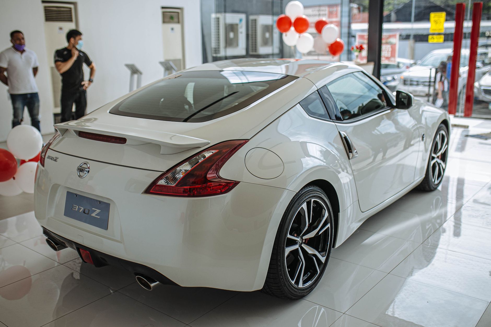Ilustrasi: Luxurious Nissan 370Z sports car showcased in a bright showroom, exuding style and performance.