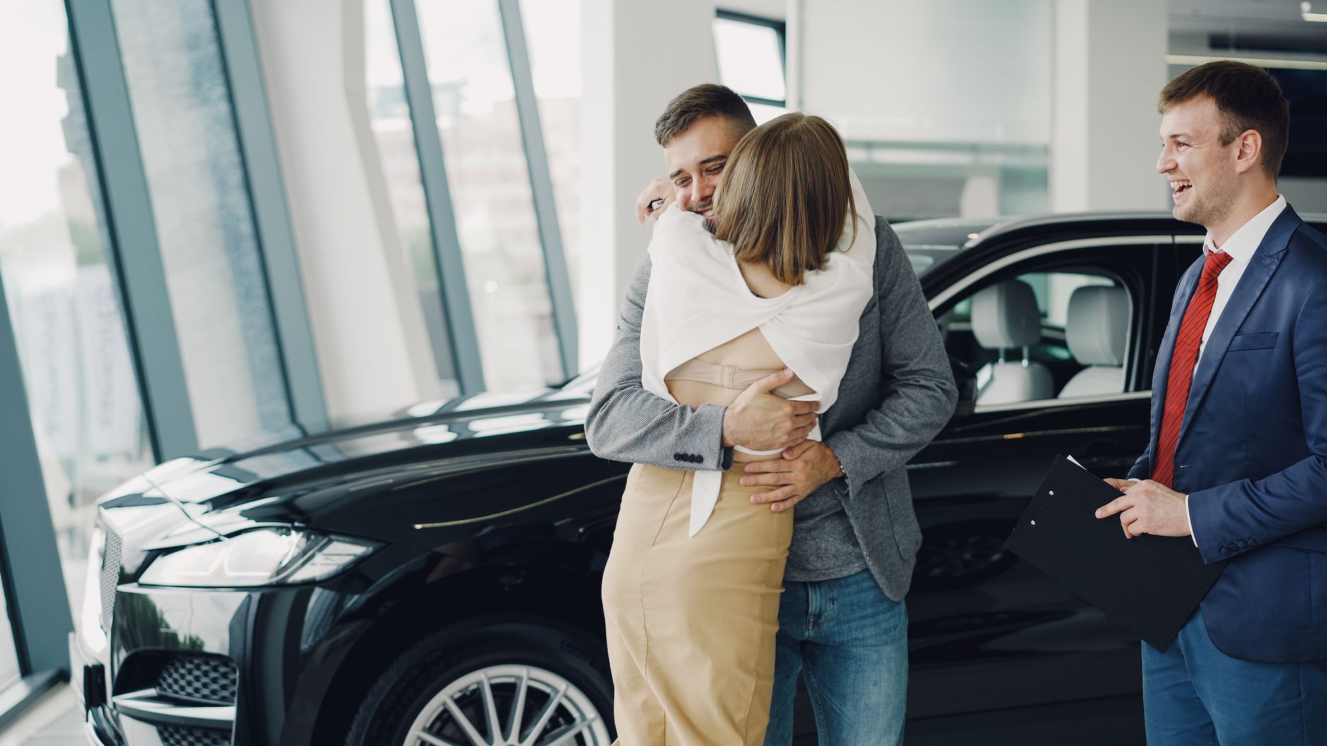 Ilustrasi: A couple embraces joyfully in a car showroom after purchasing a new vehicle.