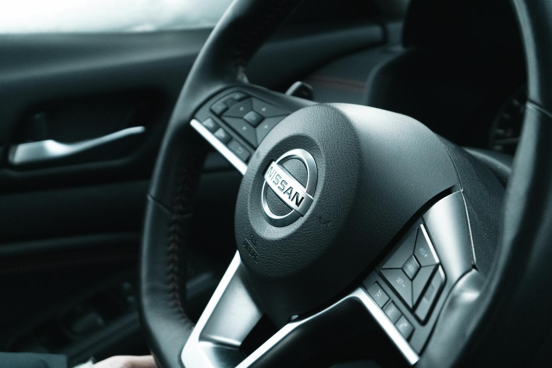 Ilustrasi: Detailed view of a Nissan car steering wheel in a modern vehicle interior.